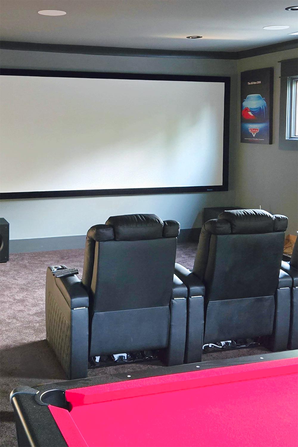Two black leather recliners facing a large projection screen