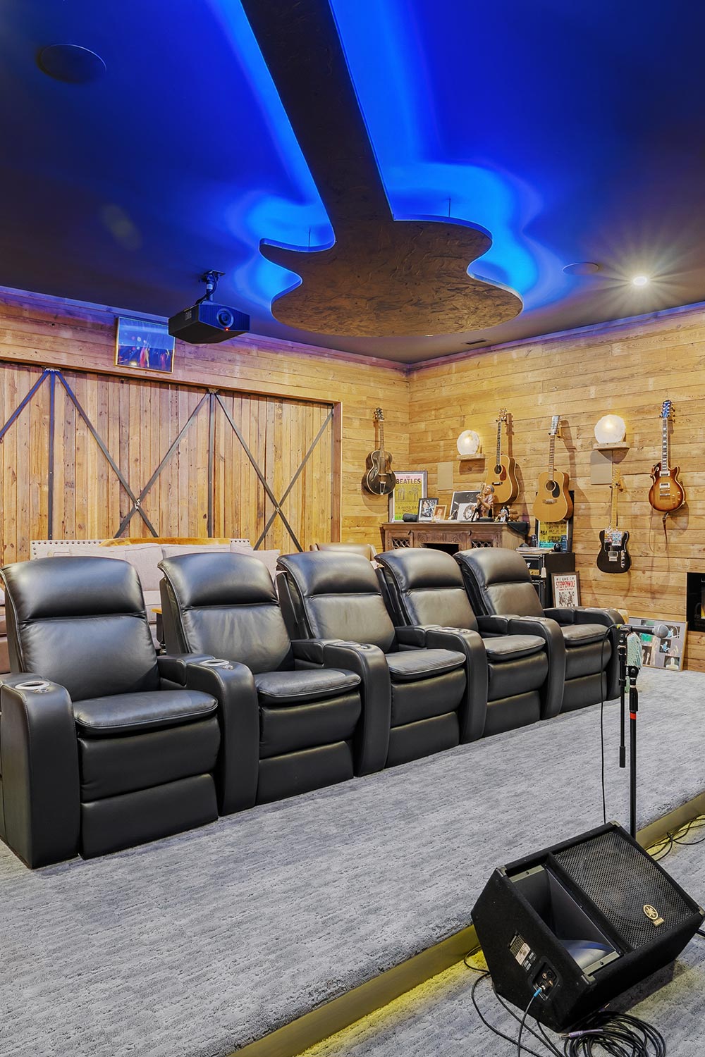 Four black theater recliners under a guitar-shaped blue light