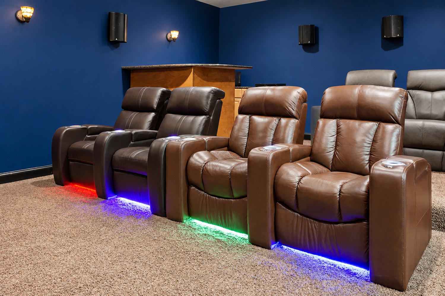 Row of brown leather home theater recliners with colorful under-seat LED lighting