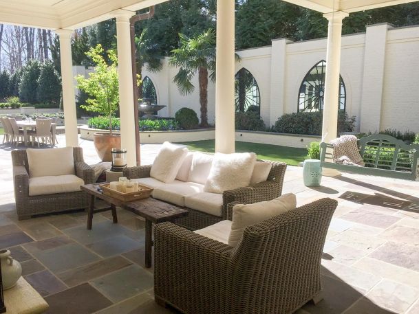 Covered outdoor patio with wicker seating and a swing facing a garden