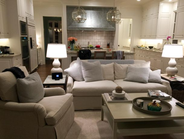 Cozy living room with white sofas open to a large kitchen