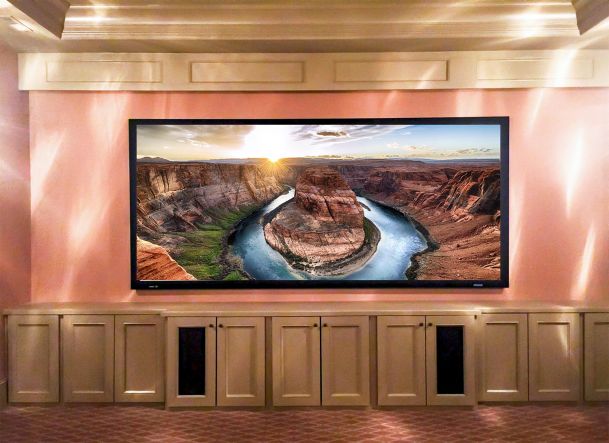 Large theater projection screen showing canyon above beige cabinets
