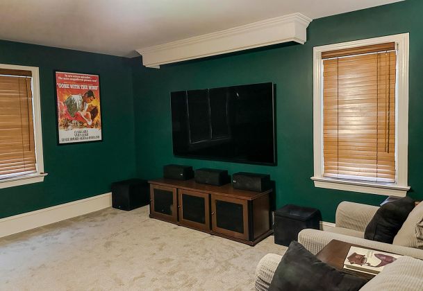 Green media room with a large flat screen TV and speakers