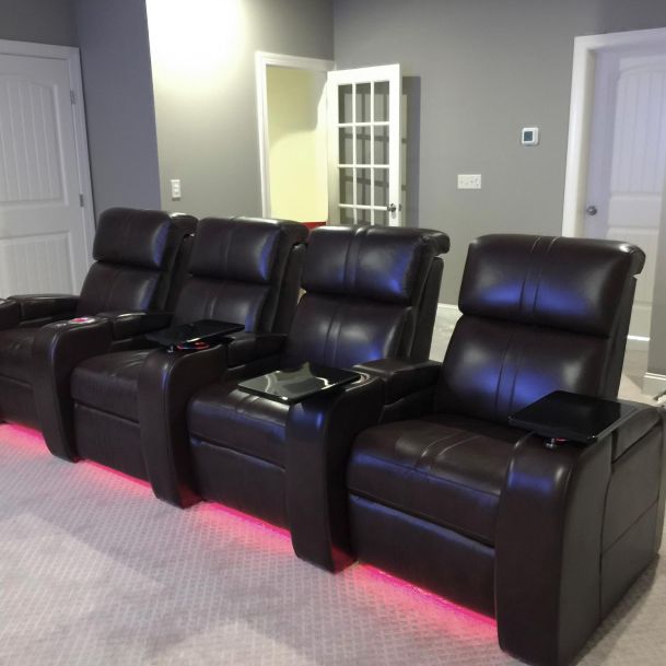 Row of four dark leather theater recliners with pink LED underglow