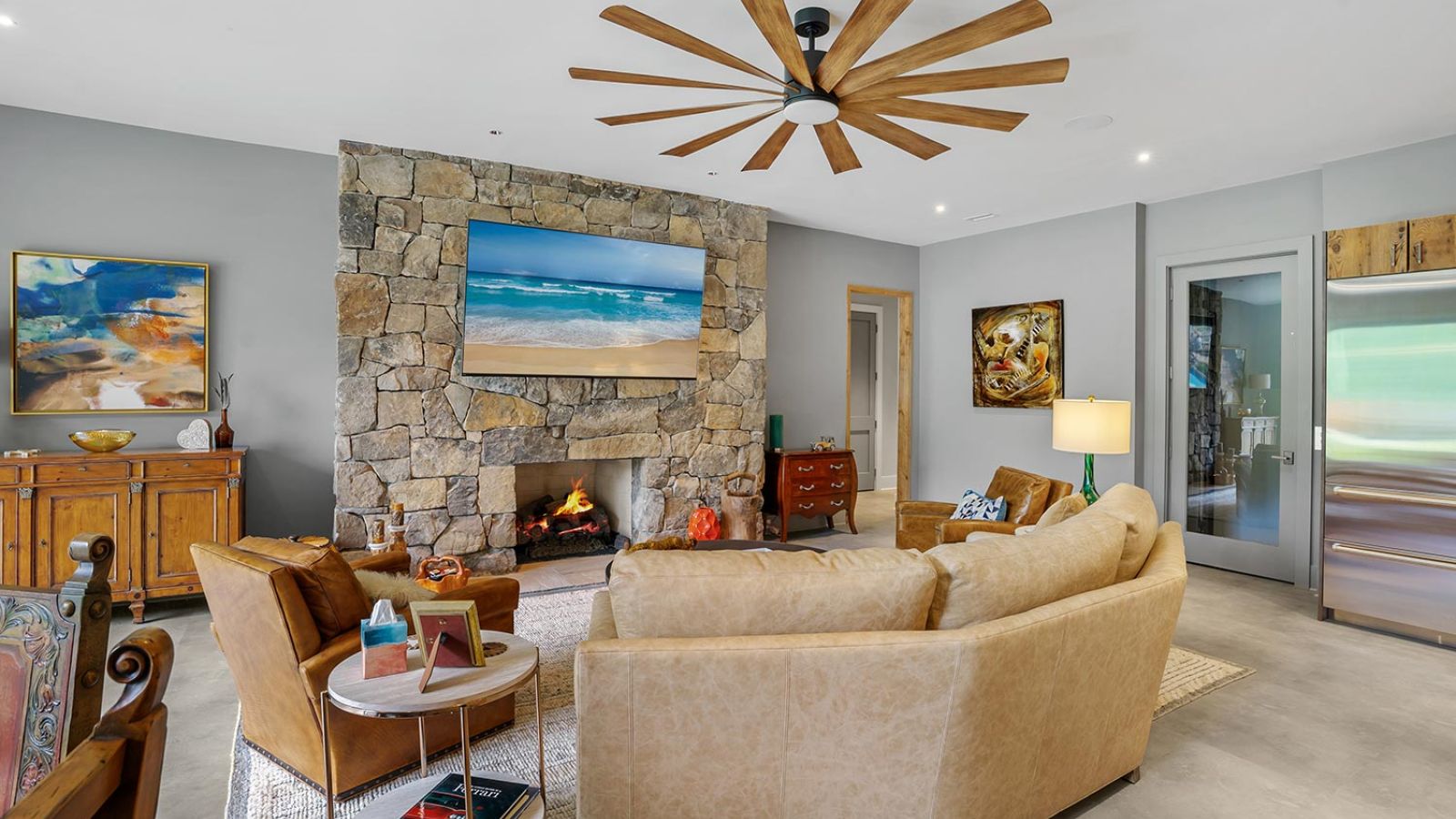 Living room with leather sofas, a stone fireplace, and a wall-mounted TV