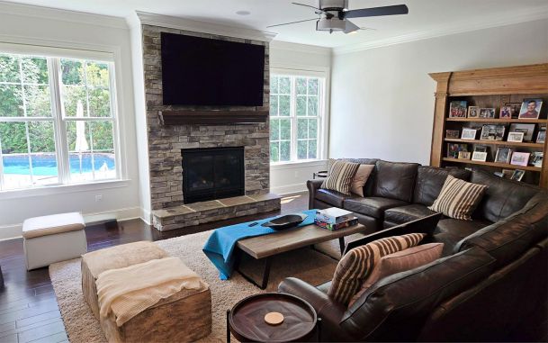 Living room with stone fireplace TV and brown leather sectional sofa