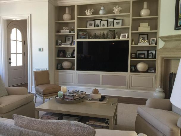 Living room with built in beige shelving framing a large wall mounted tv