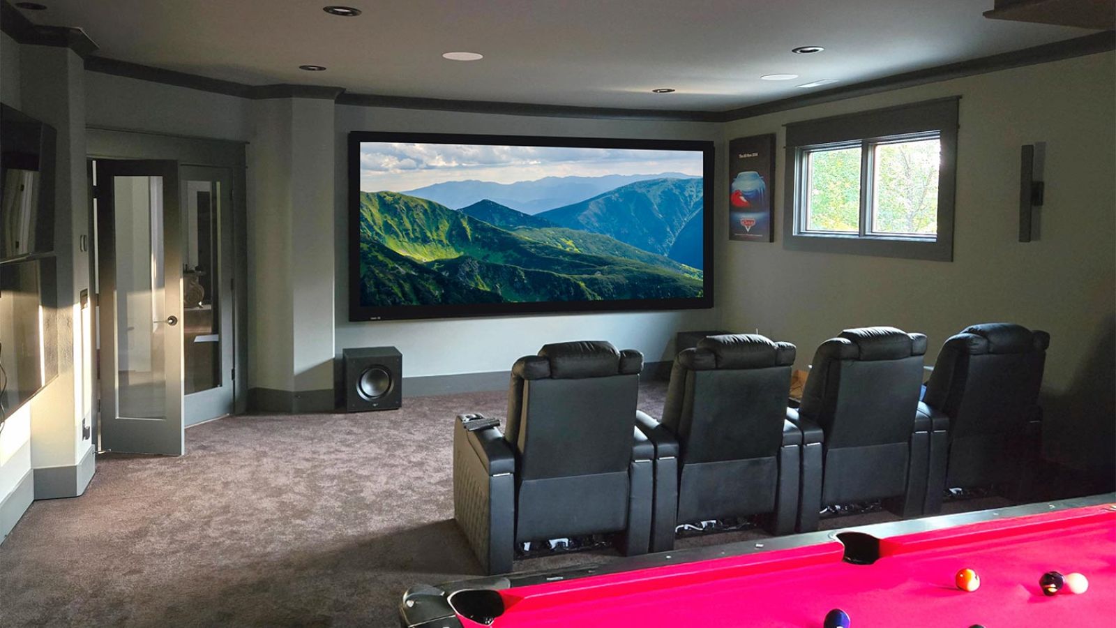 Multipurpose room with a red pool table, leather seating, and large screen