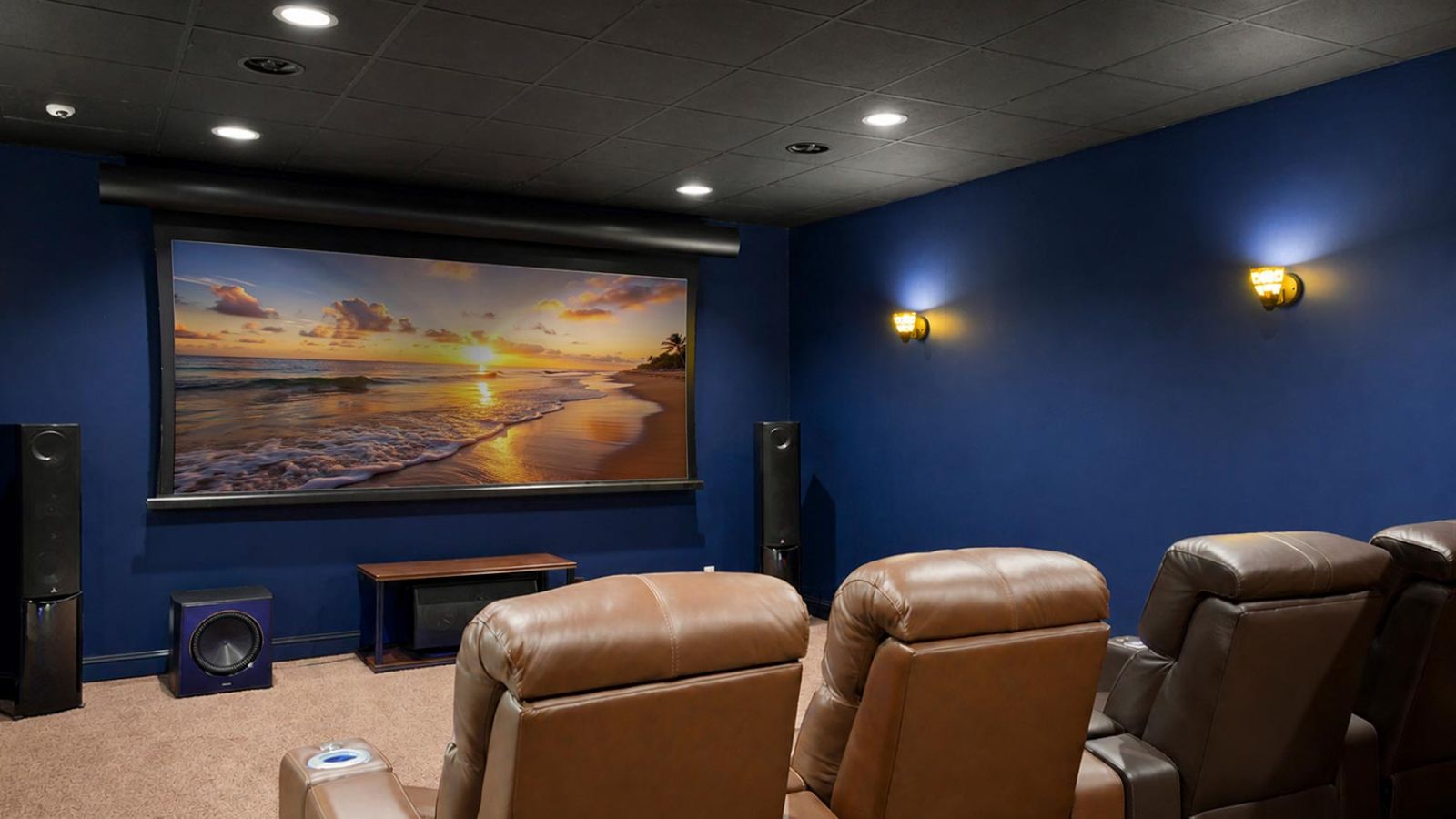 Home theater with blue walls and brown leather seating facing a large screen