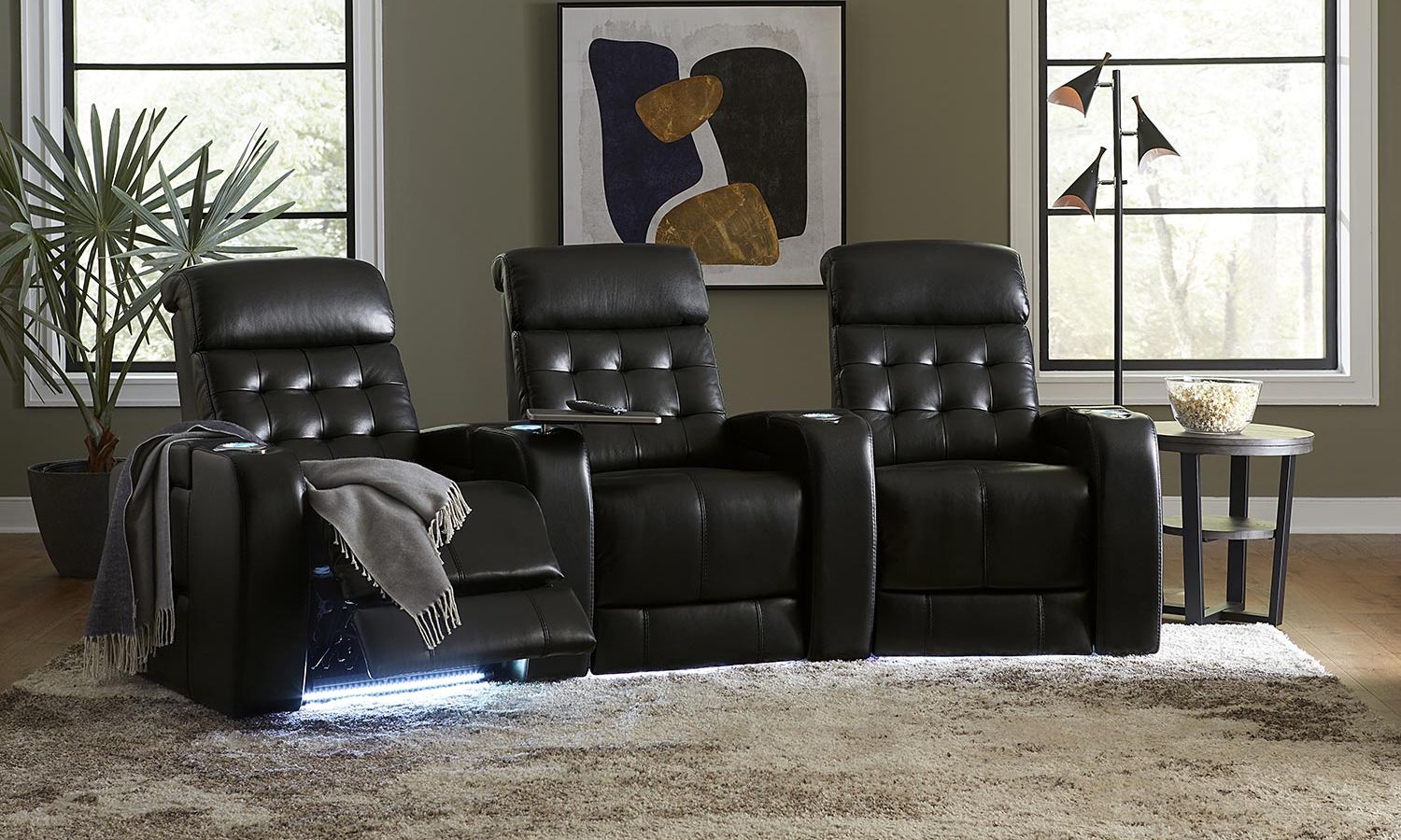 three black leather theater seats with a throw blanket