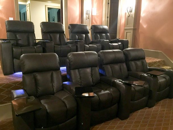 Two rows of brown leather recliner seats in a home theater setting