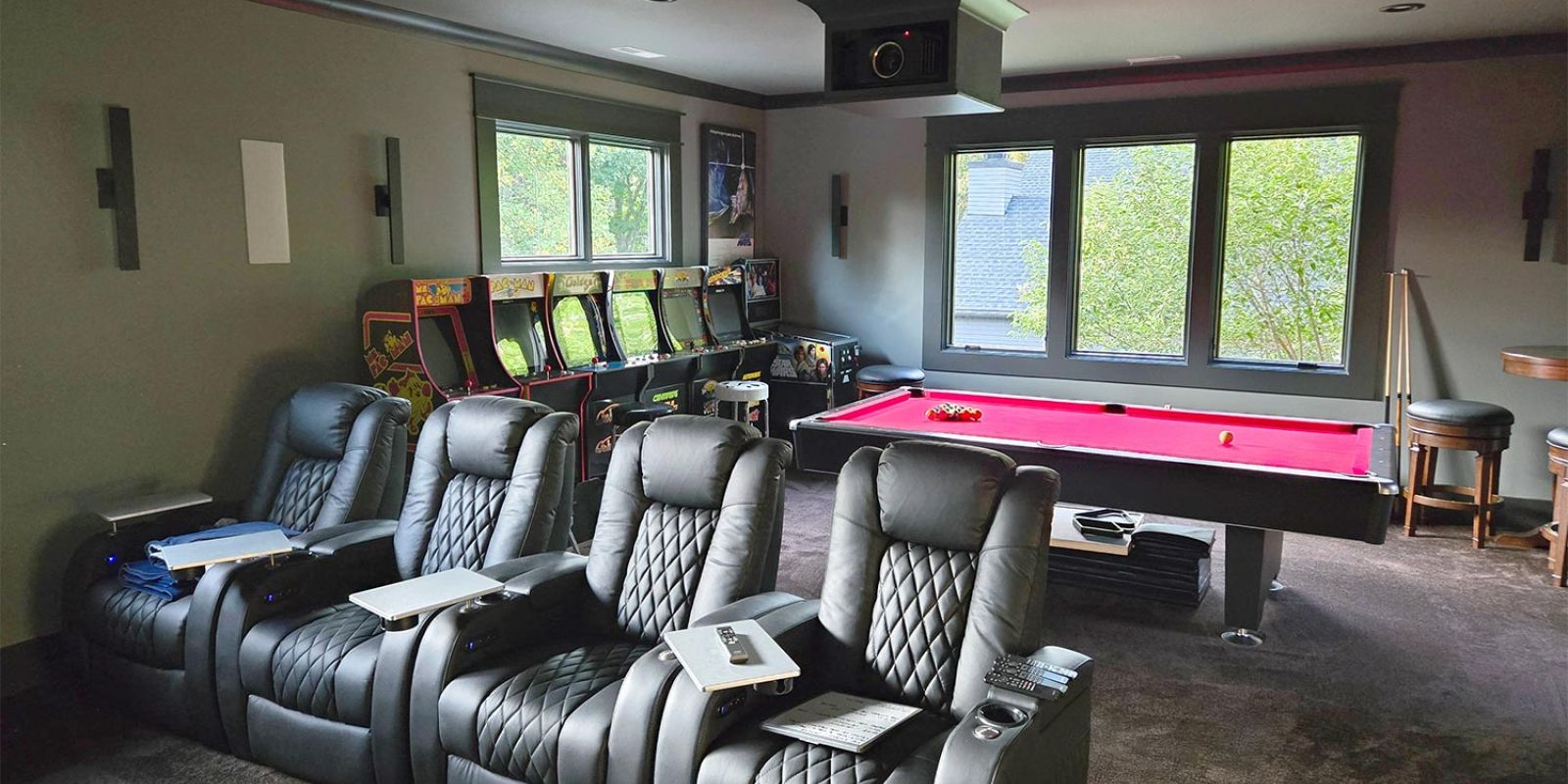 Black leather theater seating next to a pool table and arcade machines