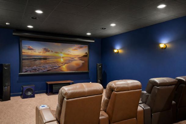 Home theater with blue walls and brown leather seating facing a large screen