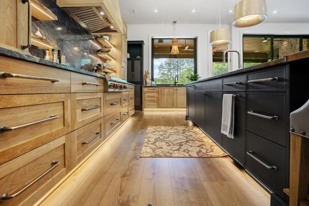 Kitchen with wood cabinets, dark island, and under-cabinet floor lighting
