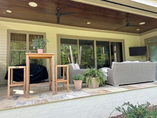 Outdoor patio with wicker seating, a wooden table, and a wall-mounted TV