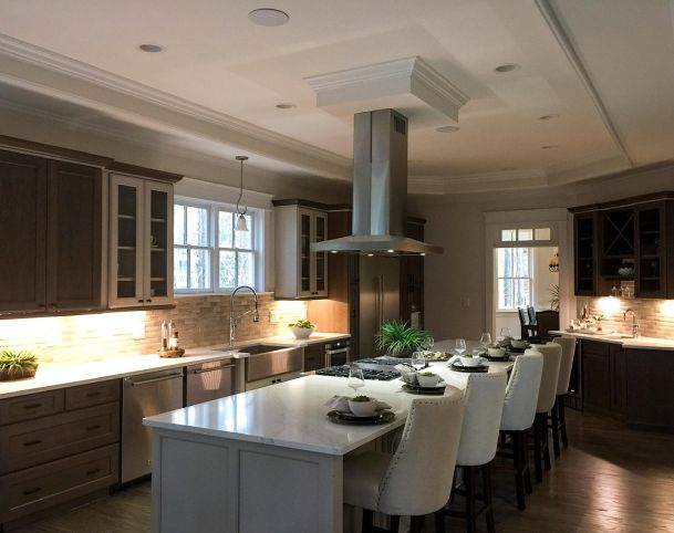 Kitchen with large marble island white bar stools and cabinet lighting