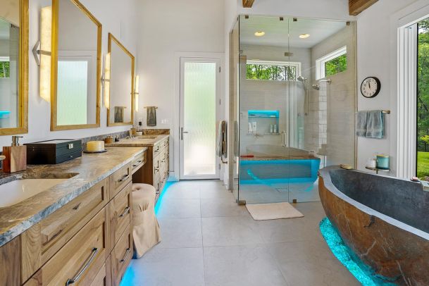 Modern bathroom featuring a stone tub, glass shower, and blue LED lighting