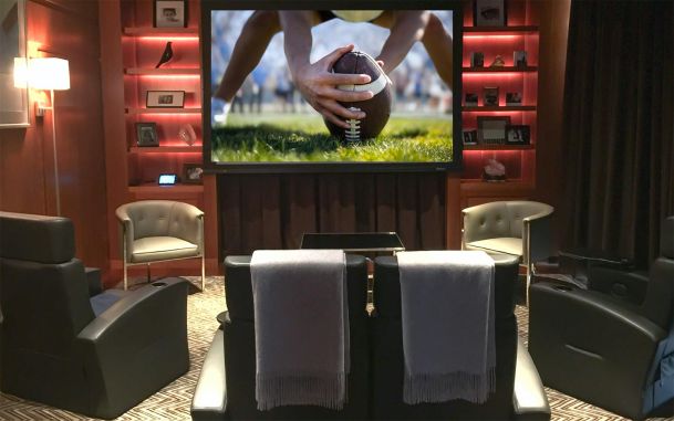 Home theater with large screen showing a football and red back-lit shelves