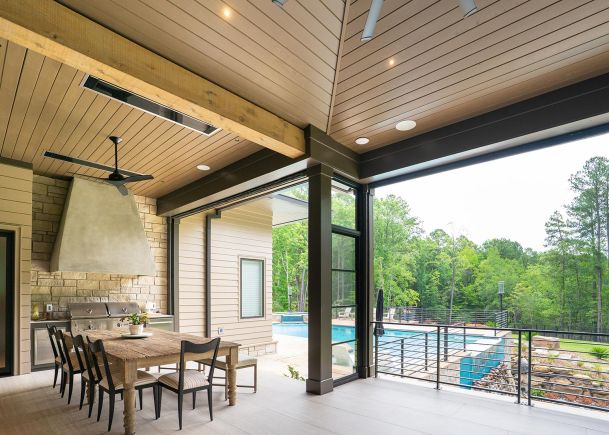 Covered outdoor patio with dining table and grill overlooking a swimming pool