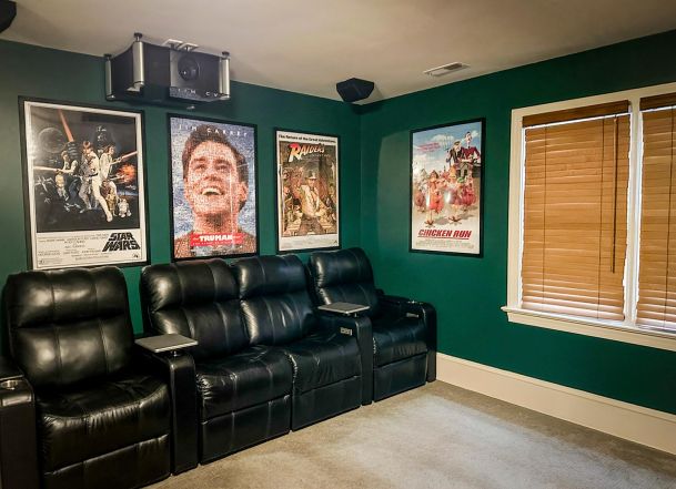 Black leather theater seating in a green room with framed movie posters